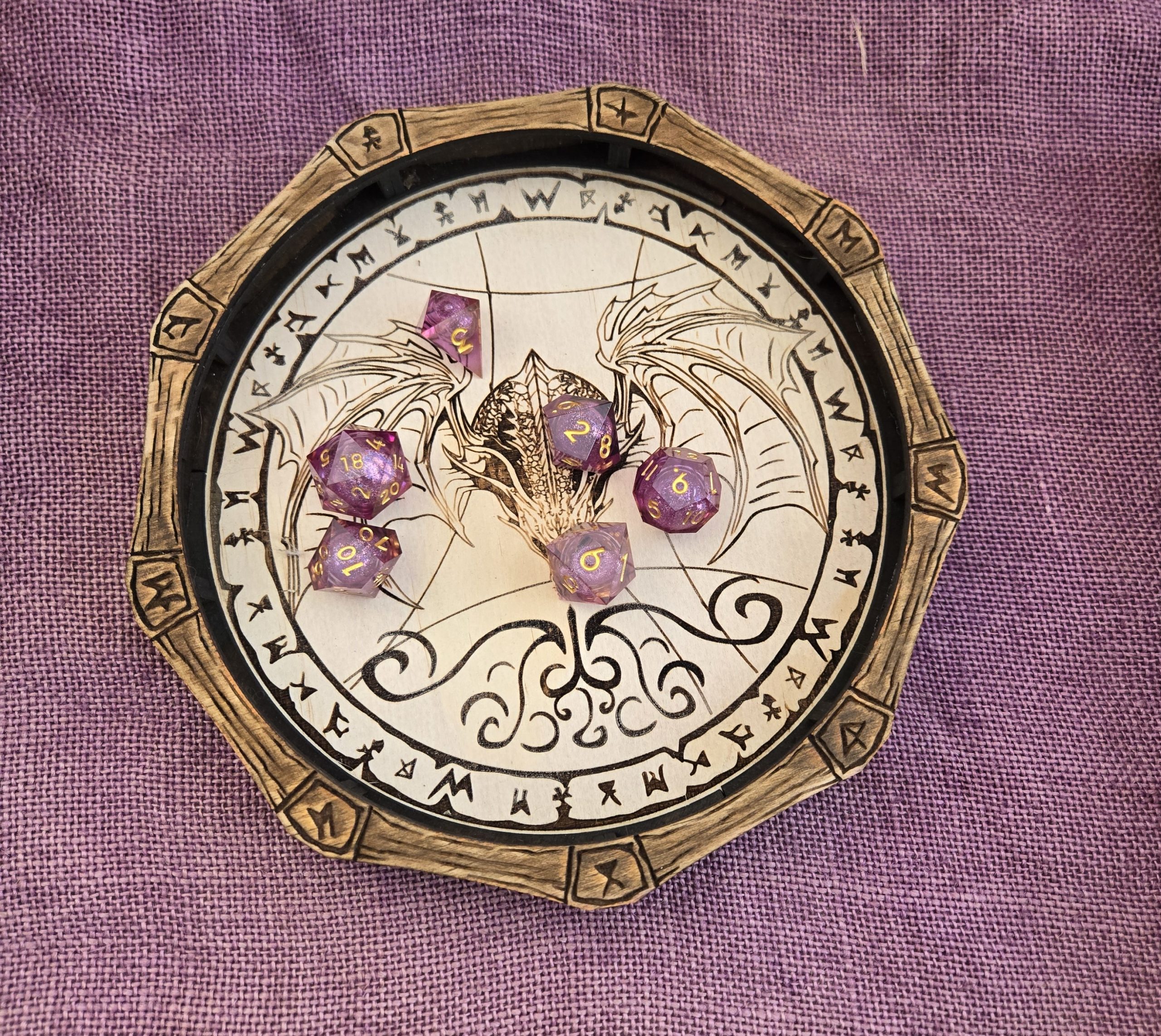 Wooden dragon-design dice tray holding sparkly purple dice, created for tabletop role-playing games.